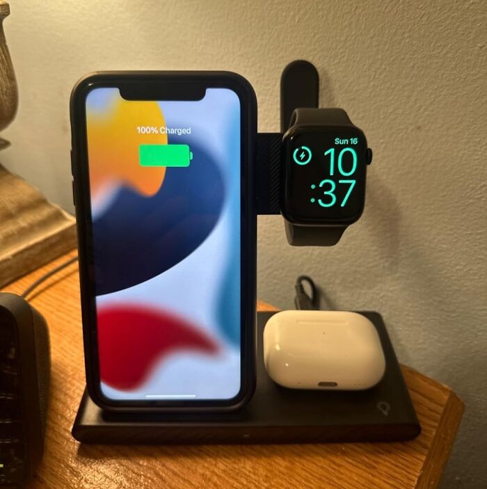Phone, smartwatch, and earbuds on a charging dock, illustrating work from home tech essentials.