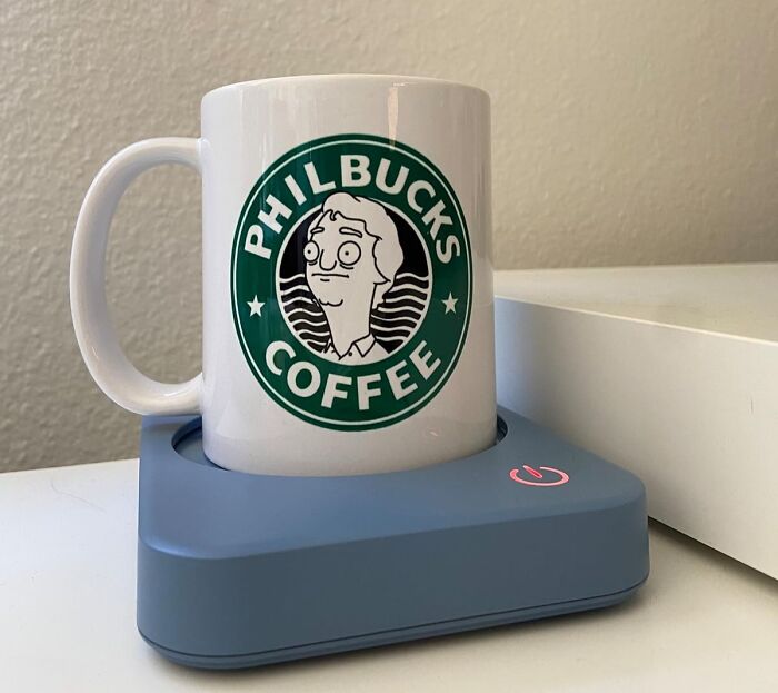 A Philbucks branded mug on a blue mug warmer, showcasing home tech essentials.