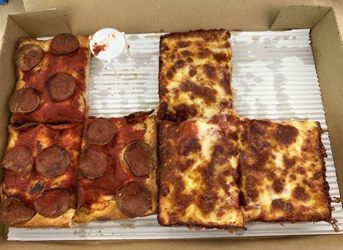Rectangular pizza with uneven toppings in a box, demonstrating food scams with half missing pepperoni.
