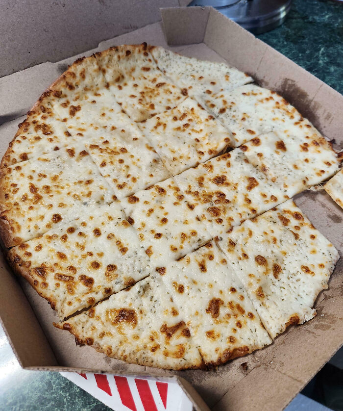 Cheese pizza cut into uneven squares, representing food scams in a cardboard box.