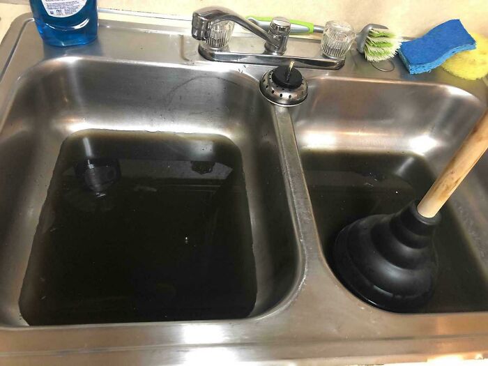 Clogged sink with standing water and plunger, illustrating a Valentine's Day fail in the kitchen.