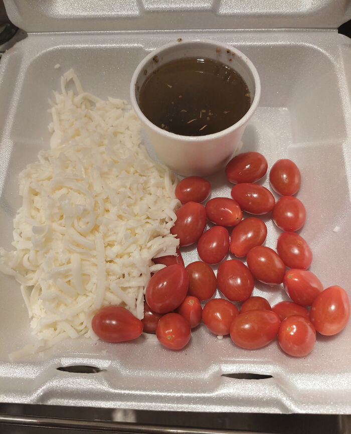 Shredded cheese and cherry tomatoes next to a small cup of sauce; example of food scams.