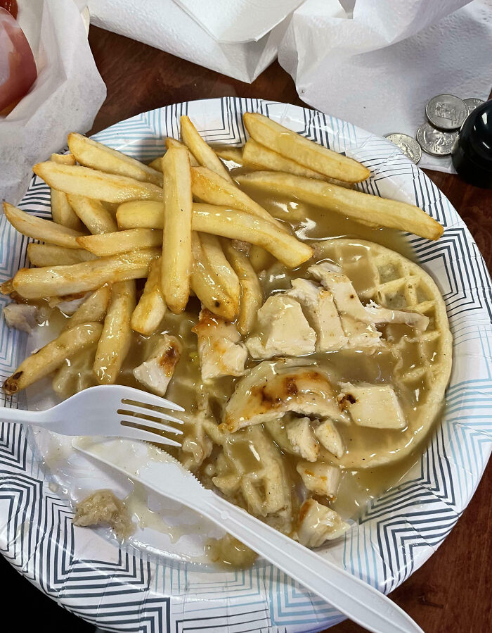 Plate of fries and chicken on a waffle with gravy, highlighting infuriating food scams.