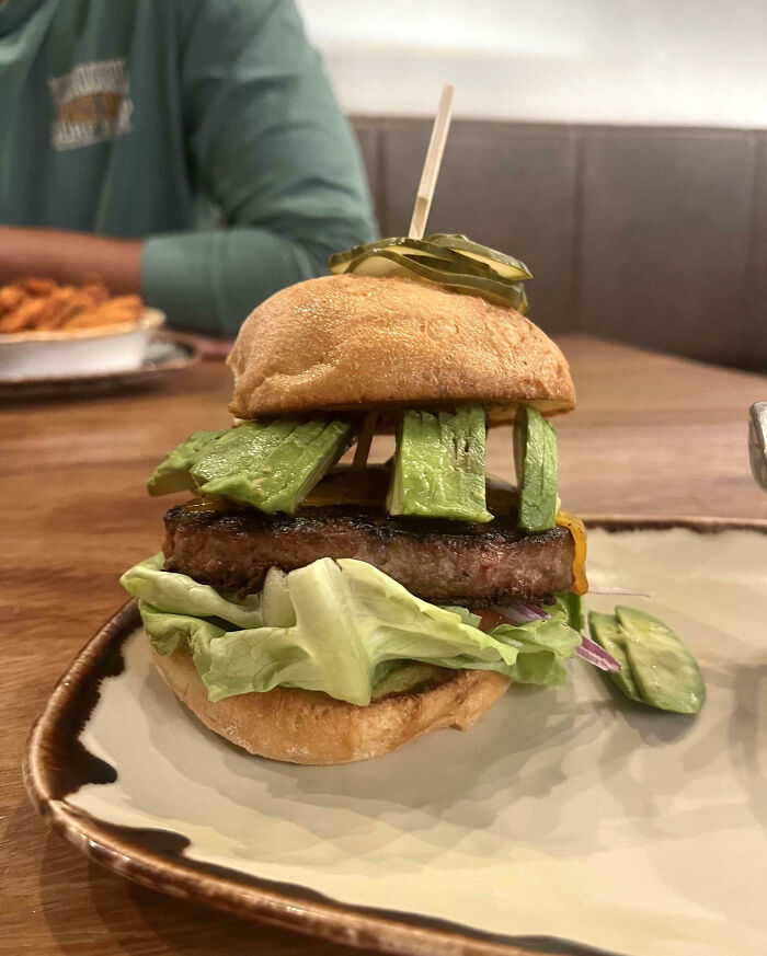 Unusual burger presentation with minimal avocado slices, highlighting food scams in restaurant servings.