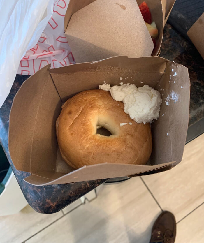 Bagel with a small amount of cream cheese in a cardboard box, illustrating a food scam.