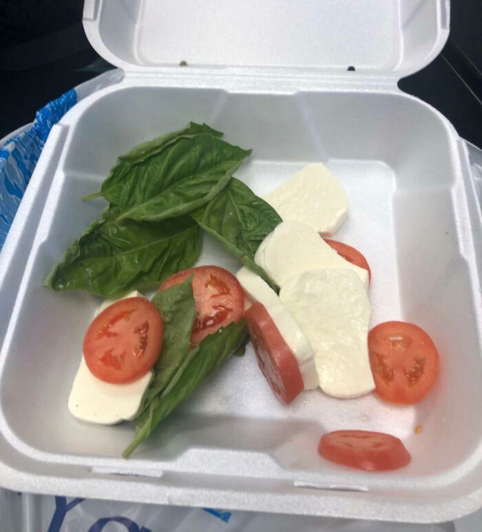 Caprese salad in a styrofoam box, highlighting food scams with minimal ingredients.