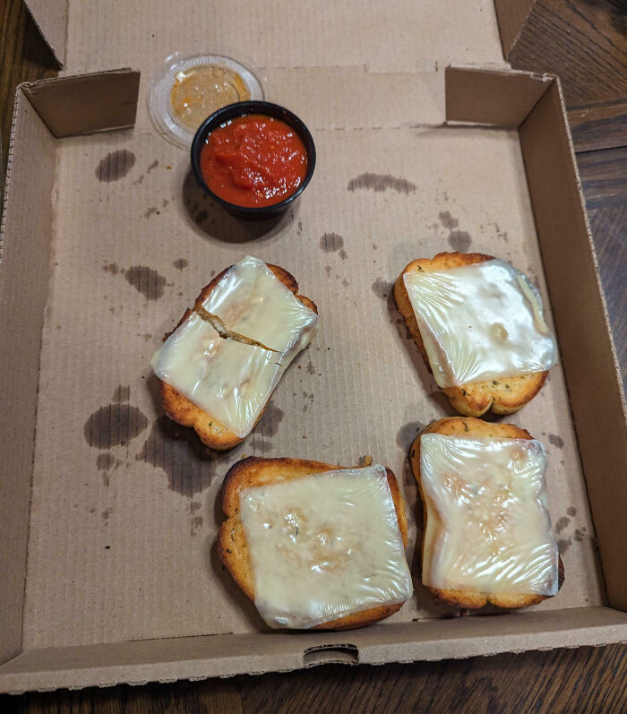 Cheese-covered bread slices in a box, with two dip sauces, illustrating food scams.