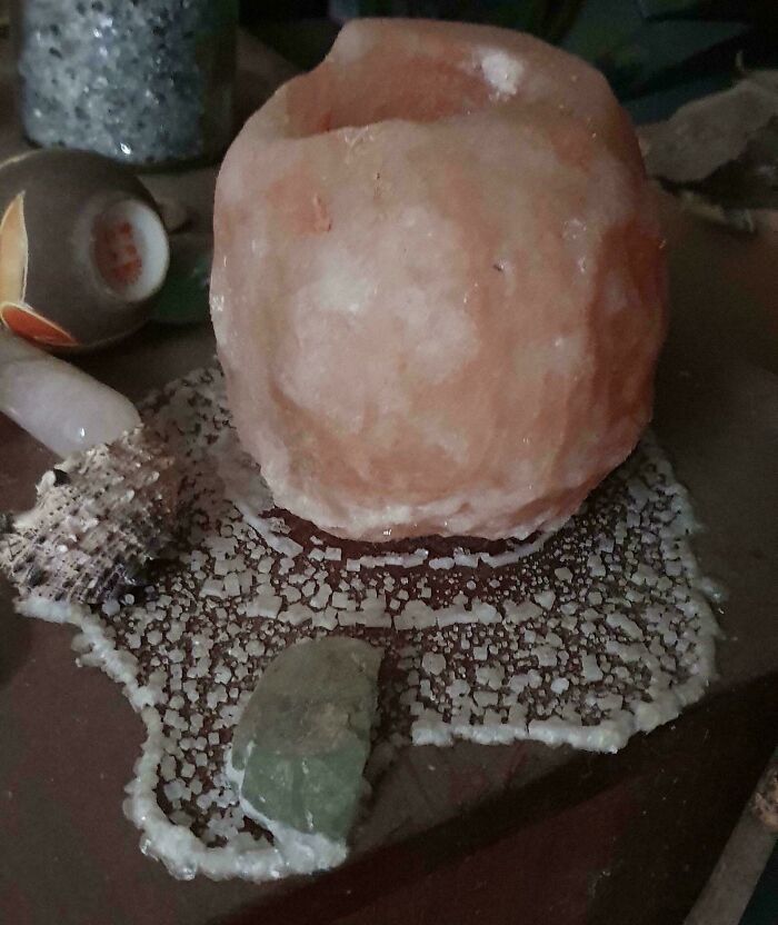A mildly interesting salt lamp surrounded by crystal formations on a wooden surface.