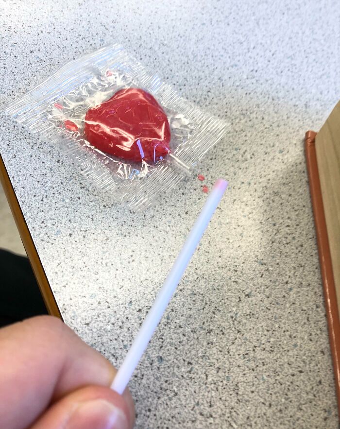 Valentine's Day fail with a broken lollipop stick next to an unopened heart-shaped candy.