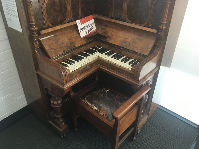 Old wooden organ with unique L-shaped design and ornate carvings, representing cool old things in a vintage setting.