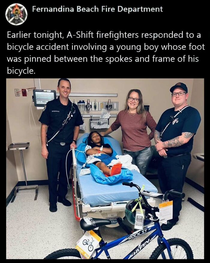 Firefighters and a woman comfort a young boy in a hospital after a bicycle accident, bringing positive moments to his day.