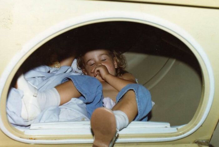 Child resting inside a vintage dryer, capturing an awkward family photo that feels incredibly sweet and nostalgic.