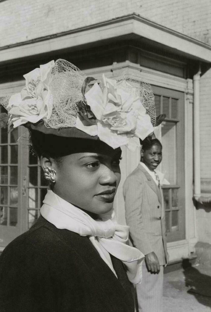 Black and white vintage photo of a woman wearing an elaborate floral hat, a classic old image from history.