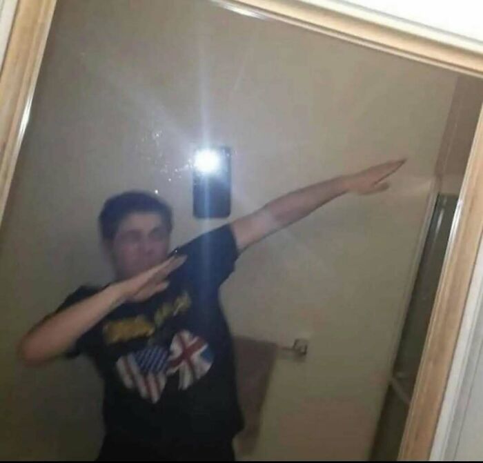 Person doing a dab pose in front of a mirror with phone flash, one of the weird side of the internet pics.