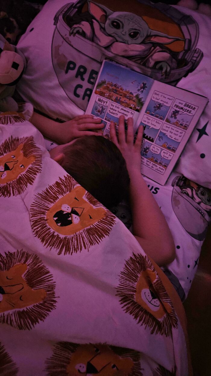 Child reading a bedtime story under lion-themed blanket, showcasing wholesome dads doing their best parenting moments.