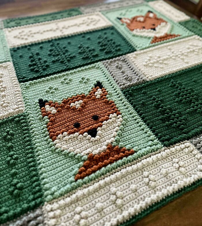 Crochet masterpiece featuring a detailed fox design on a textured green and cream handmade crochet blanket.