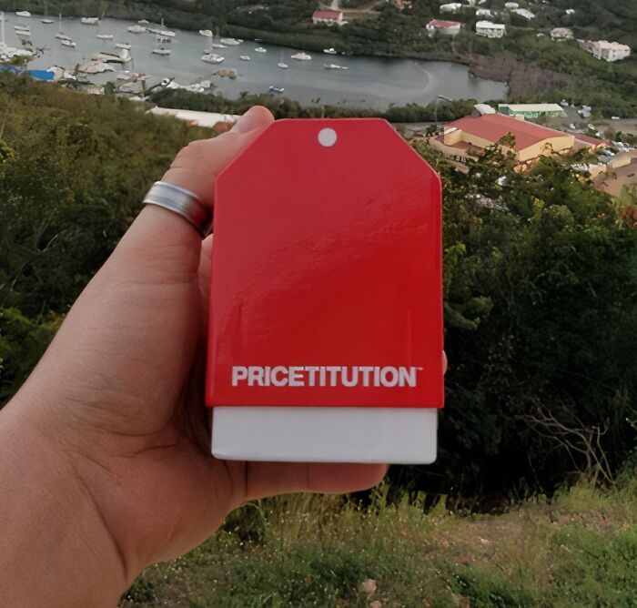 Hand holding a Sharktank item, a red product labeled "PRICETITUION," with a scenic background.