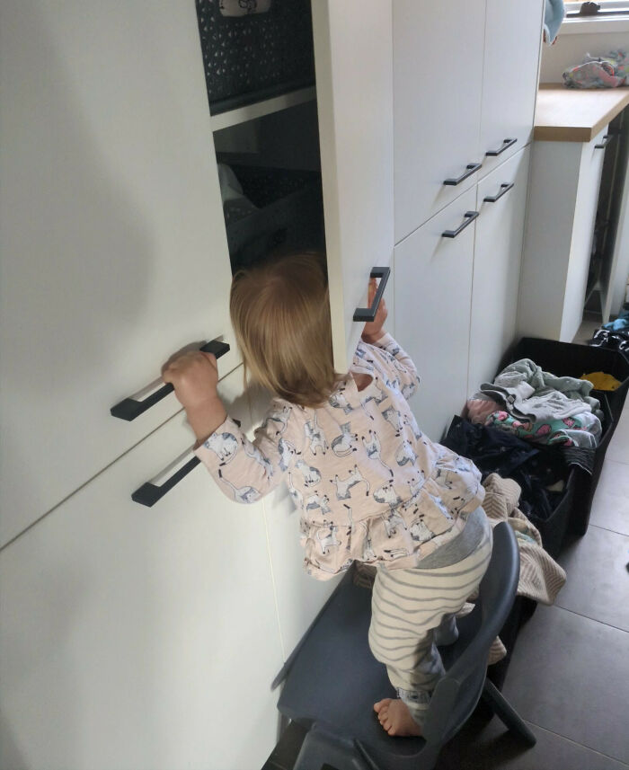 Niño subiendo a una silla para abrir un armario en la cocina, mostrando una de las tonterías divertidas que hacen los niños.