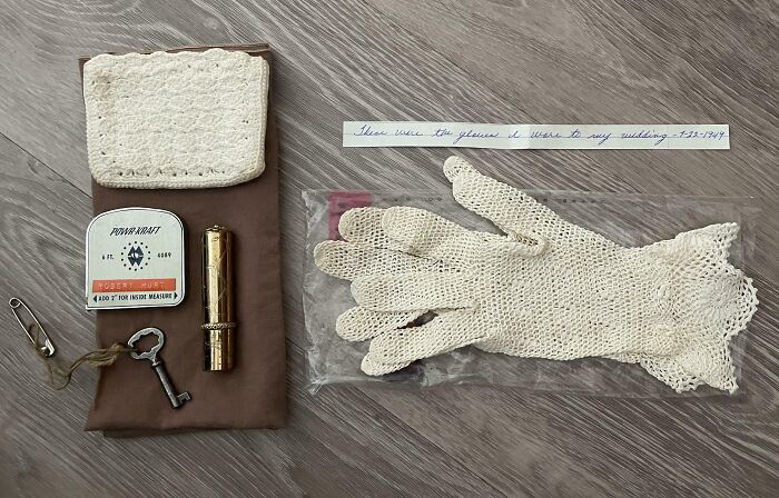 Collection of cool-old-things including lace gloves, vintage key, and sewing kit displayed on a wooden surface.