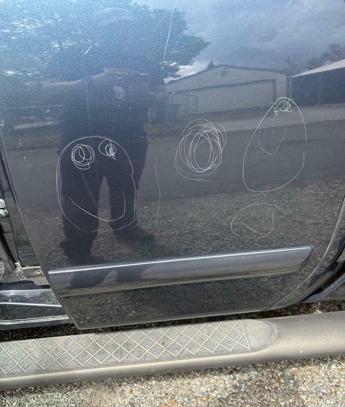 Car door with scratches resembling doodles, possibly made by clueless kids.