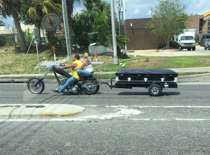 Motorcycle in Florida towing a coffin trailer on a city street, capturing a wild and unique moment.