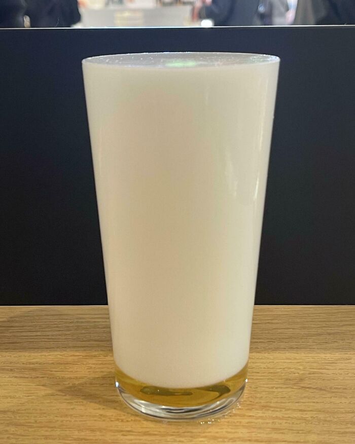 Tall glass of an intriguing Japanese drink with a milky appearance on a wooden table.