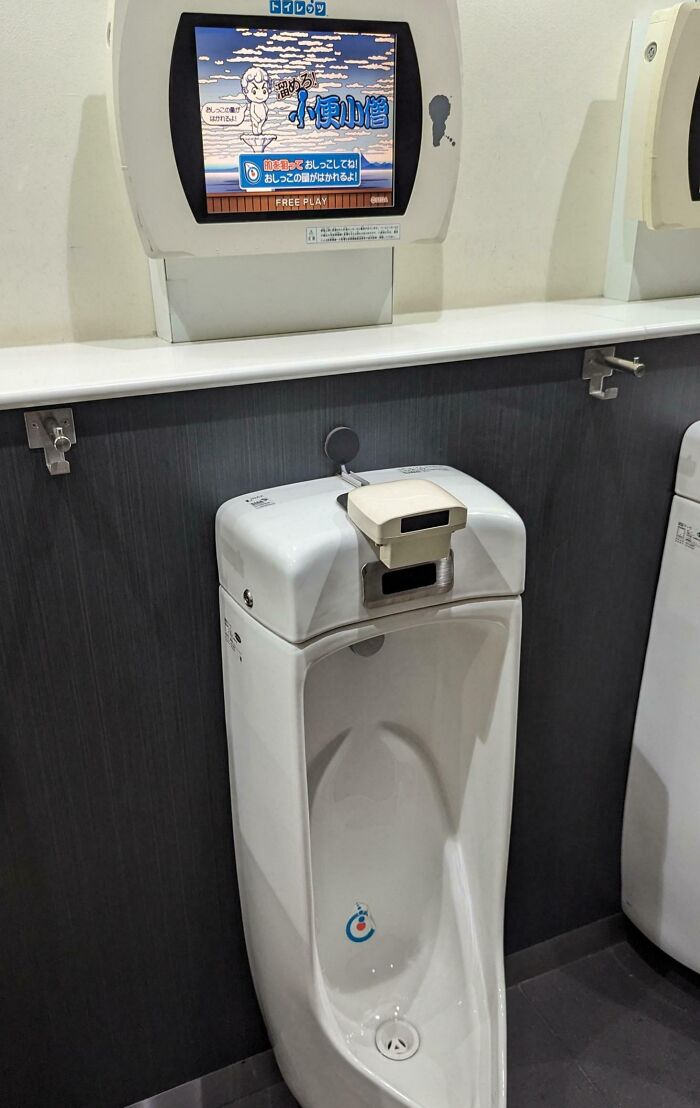 Japanese urinal with a digital screen above displaying a game, showcasing interesting technology in a public restroom.