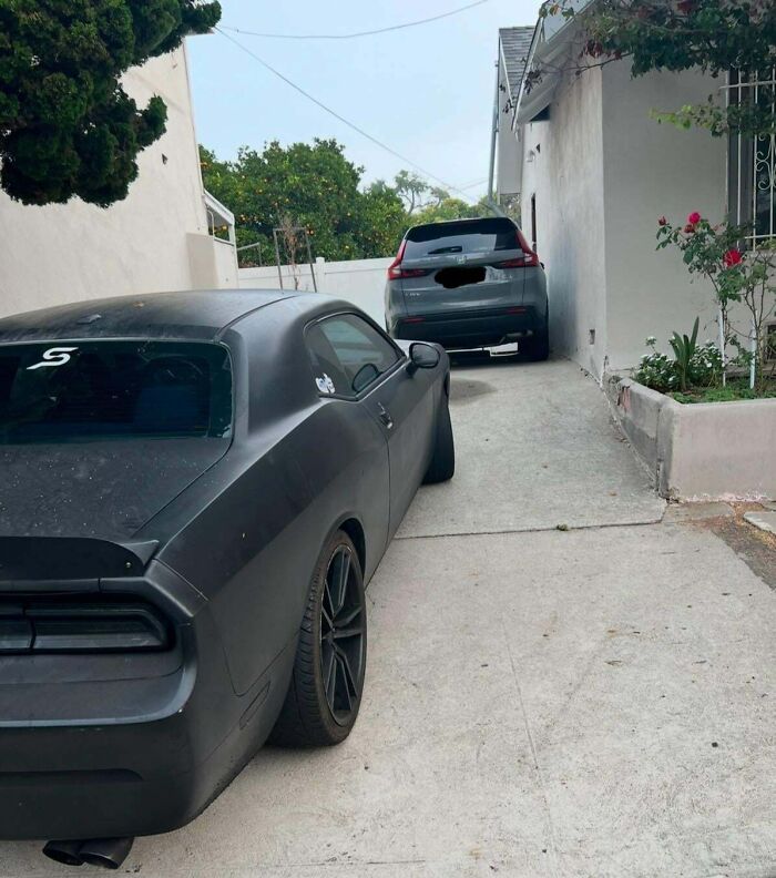 Two cars parked haphazardly in a narrow driveway, representing terrible neighbor parking issues.