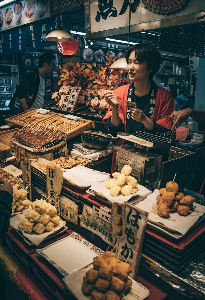 Street vendor in Japan selling skewers and fried snacks at a bustling market, showcasing interesting Japan pics.