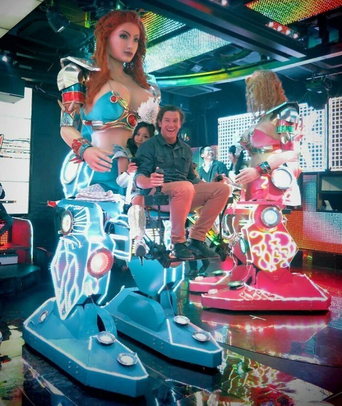 Man enjoying robot ride at a vibrant, colorful indoor venue in Japan.