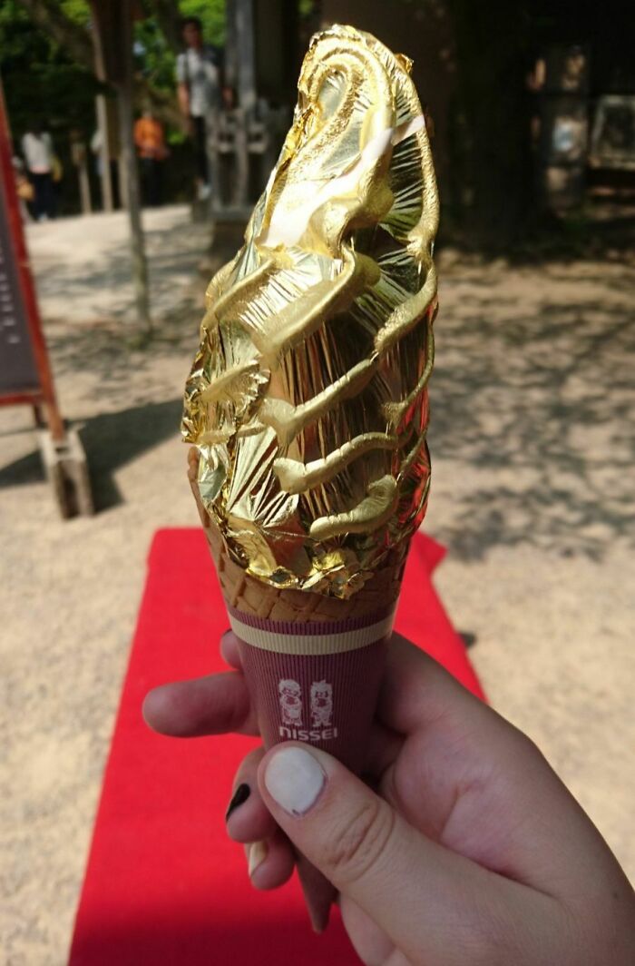 Golden ice cream cone wrapped in gold foil held by a hand, showcasing Interesting Japan Pics.