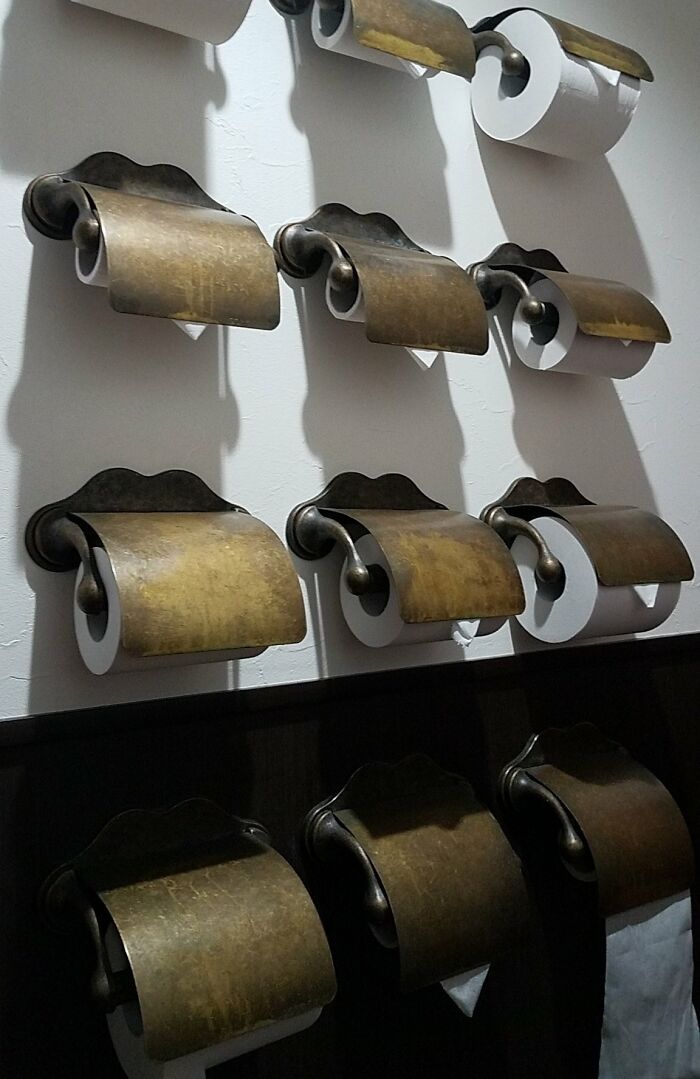 Wall with multiple vintage toilet paper holders in Japan.