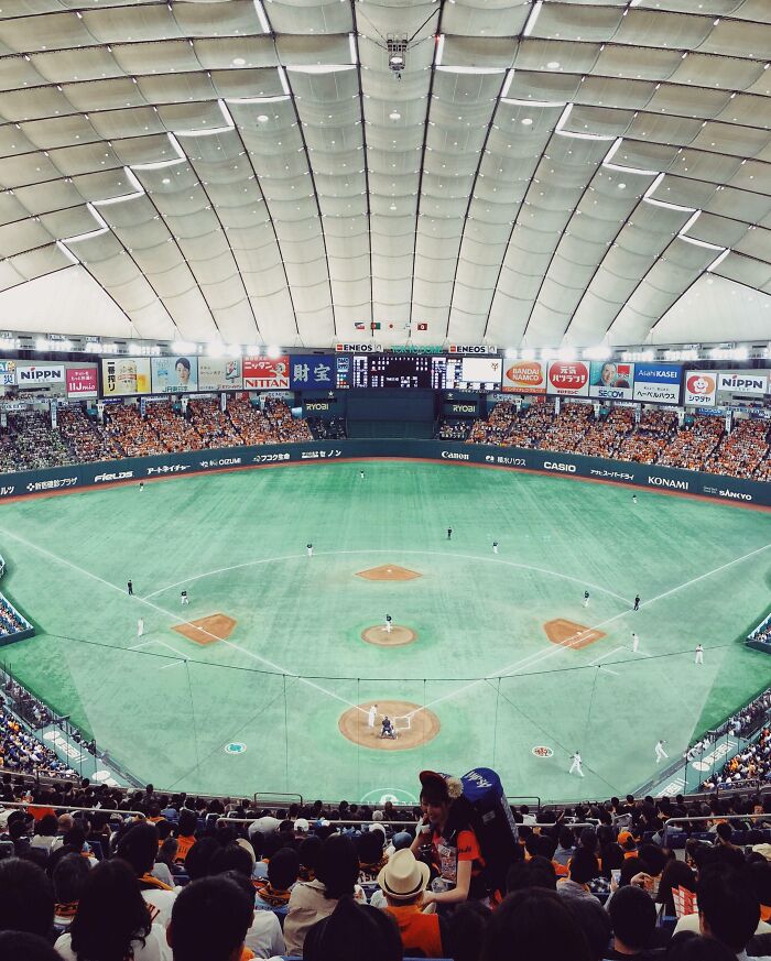 A baseball game in a large indoor stadium in Japan, with spectators filling the seats, showcasing Interesting-Japan-Pics.