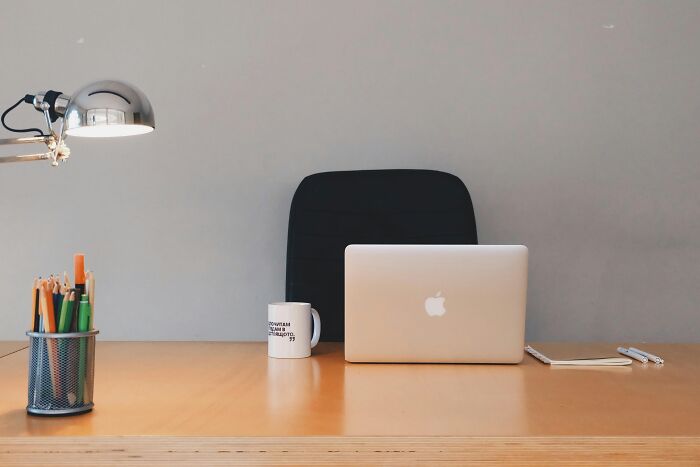 An office desk with a laptop, coffee mug, and stationery, illustrating a work setting ideal for jokes about office dynamics.