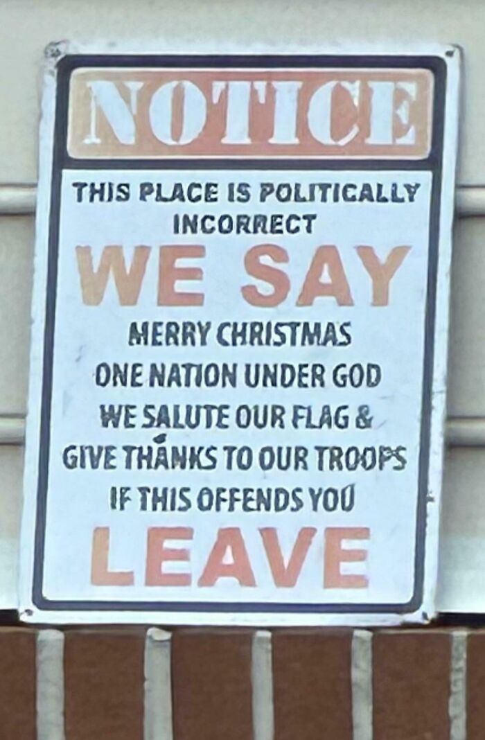 Sign on wall with politically incorrect neighbor message saying we say Merry Christmas, salute flag, and thanks to troops.