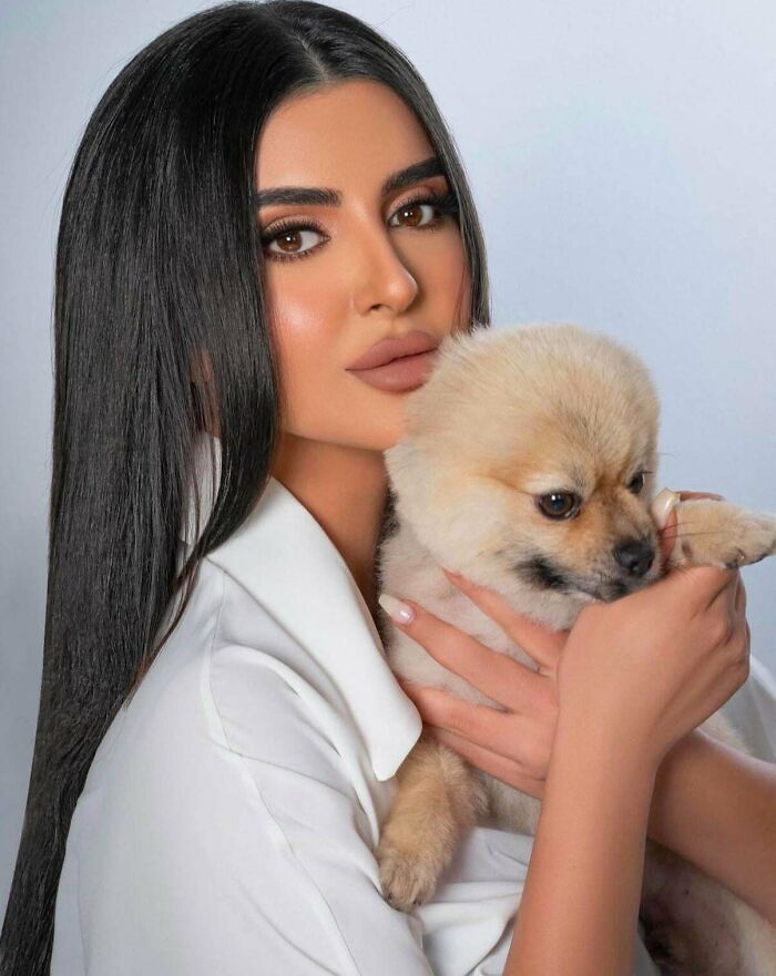 Woman with airbrushed makeup holding a small dog, showcasing Photoshop effects.