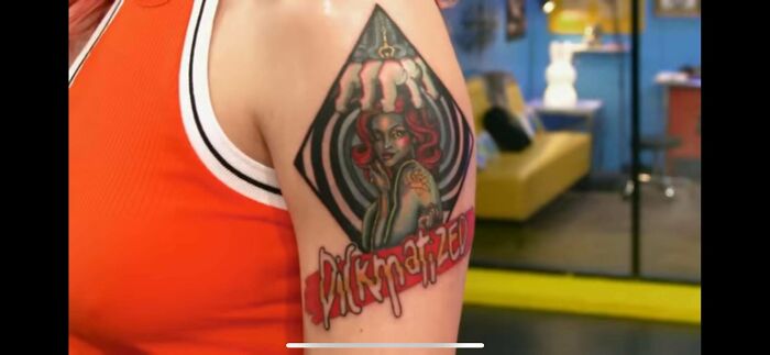 Tattoo of a woman with red hair and a distorted face on an arm, showcasing awful taste but great e*******n.