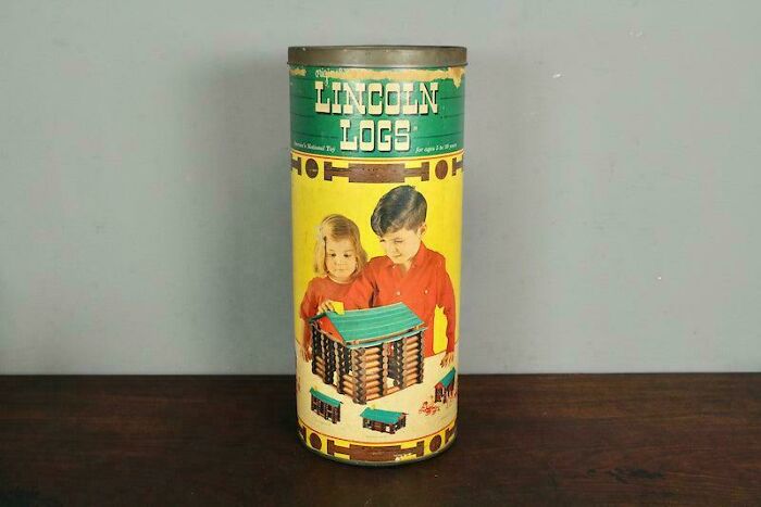 Vintage Lincoln Logs toy canister with children, evoking nostalgia.