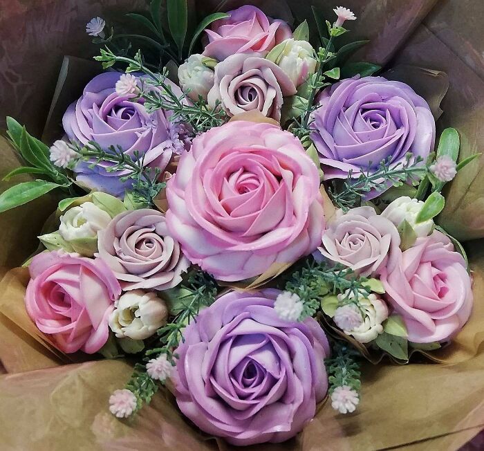Bouquet of purple and pink buttercream floral bakes arranged with green leaves, showcasing incredible bakes artistry.