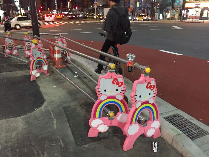 Hello Kitty-themed construction barriers on a busy Japanese street at night.