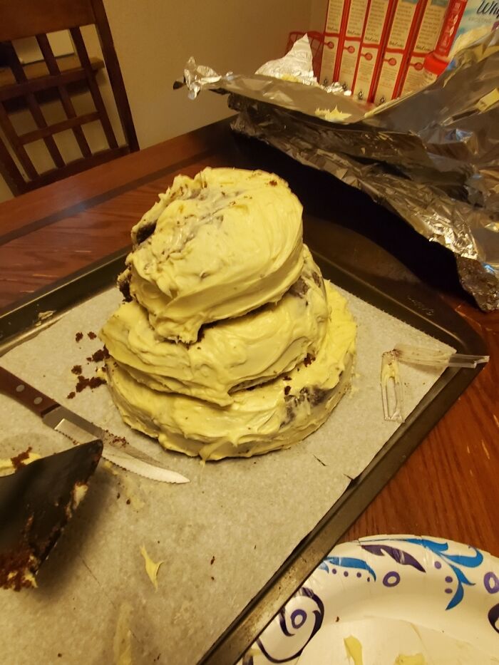 A homemade, unevenly frosted cake sitting on a table, exemplifying budget-wedding-fails.