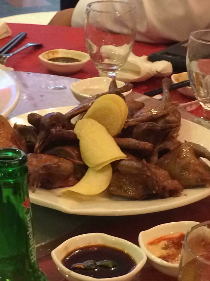 Budget wedding fails with a dish of whole roasted birds topped with potato chips, surrounded by drinks and sauces on a table.