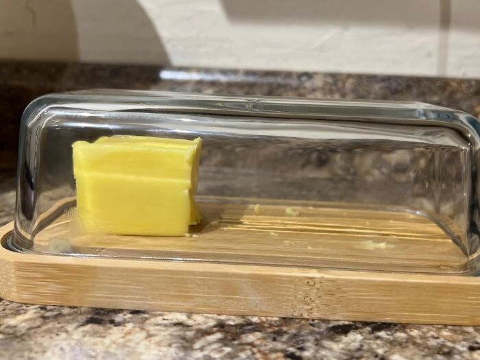 Butter dish with a clear cover and wooden base on granite countertop showing things that work hard and look good.