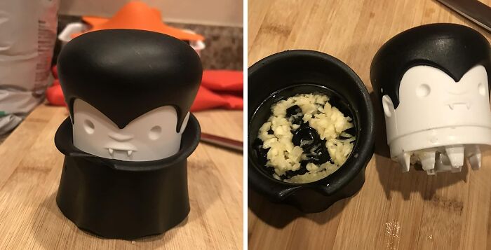 Vampire-shaped garlic crusher on wooden board showing crushed garlic inside, a stylish kitchen tool that works hard.