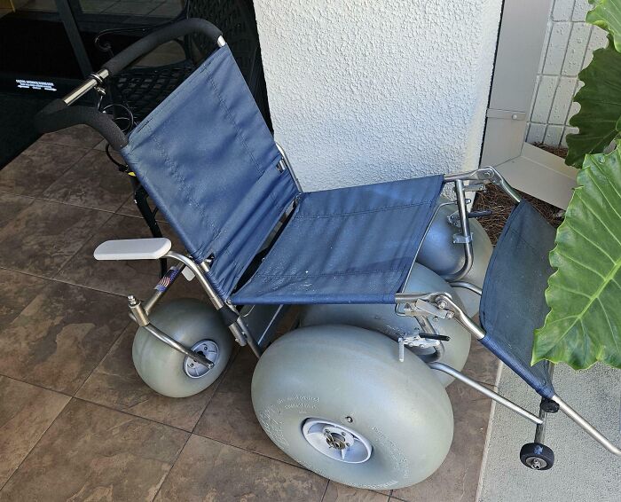 Beach wheelchair with large wheels on a tiled floor, showcasing an innovative design for easy movement in sandy Florida terrains.