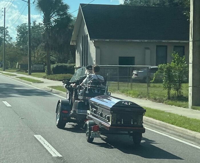 A trike motorbike pulls a casket down a sunny Florida street, capturing unique Florida-Wild-Moments.