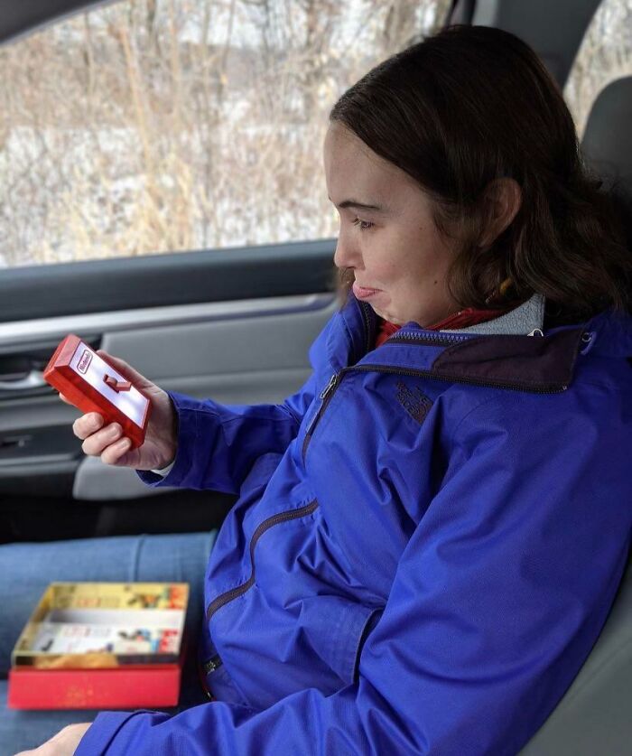 Person in blue jacket puzzled by candy box, exemplifying hilarious misunderstandings.