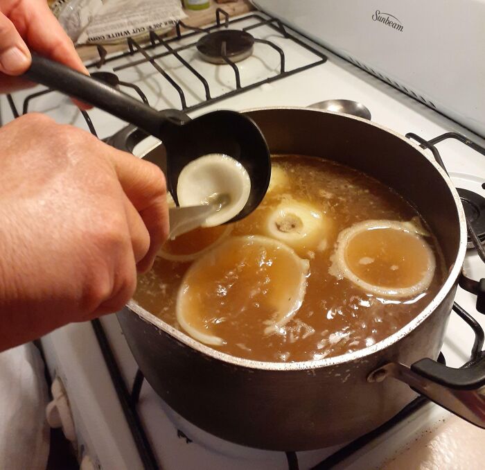 Hands ladling broth with bagels mistaken for onions, illustrating hilarious misunderstandings in cooking.