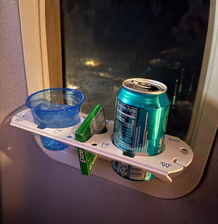 Travel tray with drink and gum on airplane window, avoiding common travel mistakes.