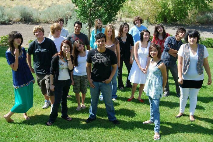 Group of teens posing outdoors on grass, capturing a nostalgic moment from their regrettable past photos.